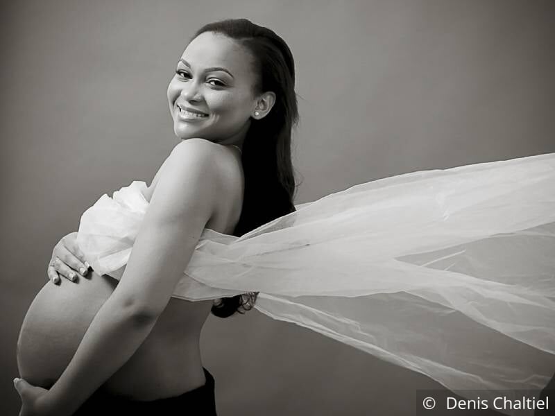 Photo en noir et blanc d'une femme enceinte avec un voile volant derrière elle.